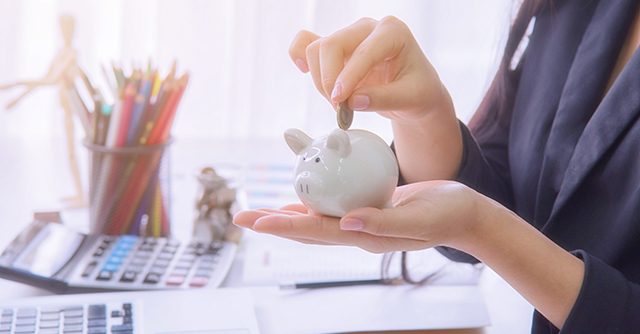 Woman dropping coin into piggy bank